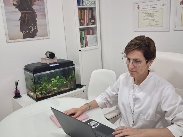 Despacho de la Dra. Helena Marcos con acuario, estantería de libros médicos y diplomas